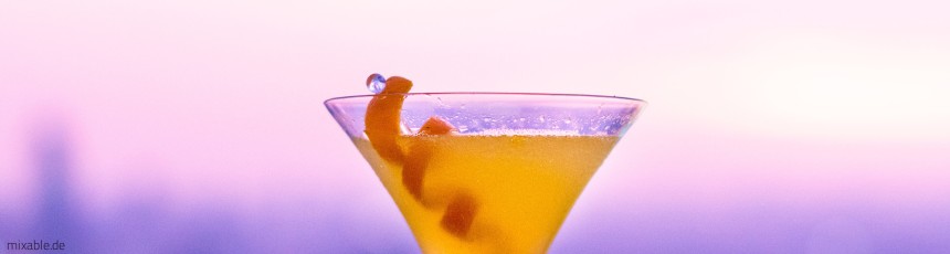 Oranger Drink vor pinkem Hintergrund.